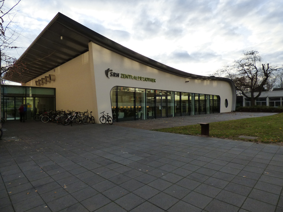 SRH Zentralbibliothek mit Fahrradständer und Glasfront, Außenansicht des Gebäudes.